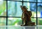 Imagem de Buda reflexivo em mesa com janela ao fundo