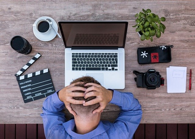 Homem em mesa de trabalho cansado visto do alto