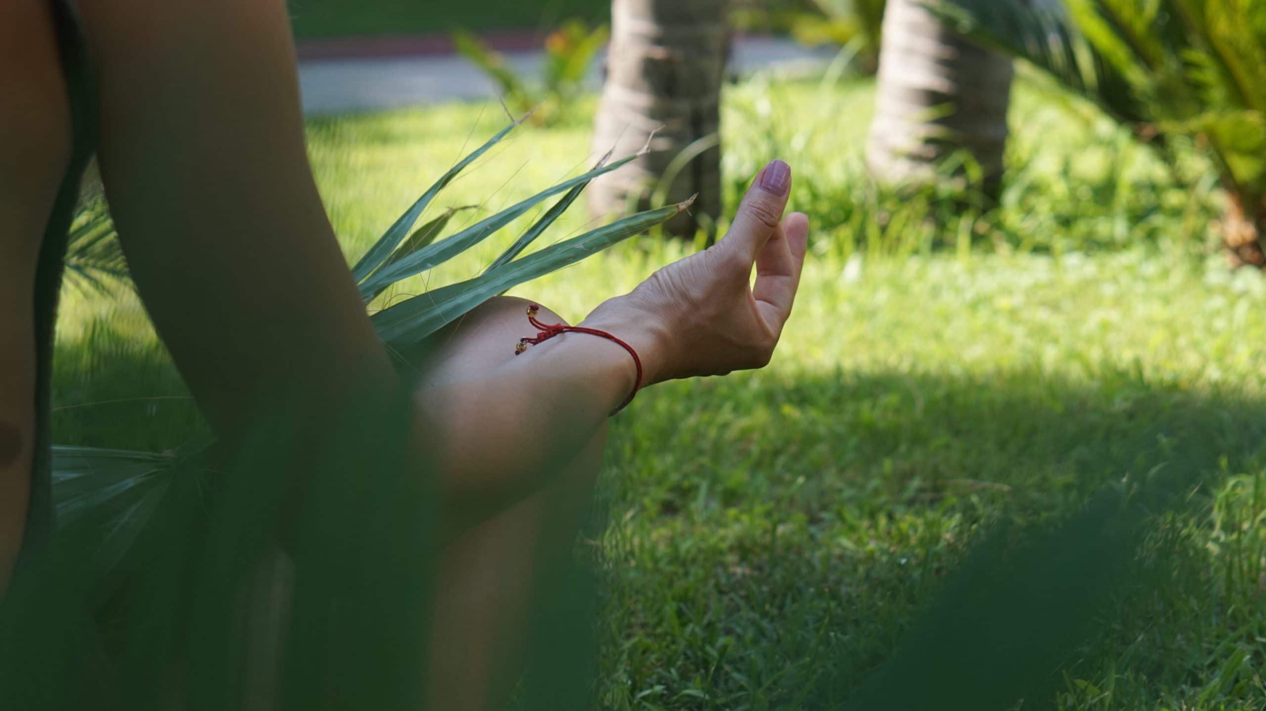 Mulher sentada em um gramado fazendo meditação