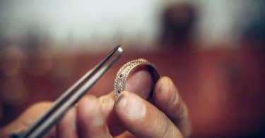 Ourives colocando um diamante em um anel com uma pinça.