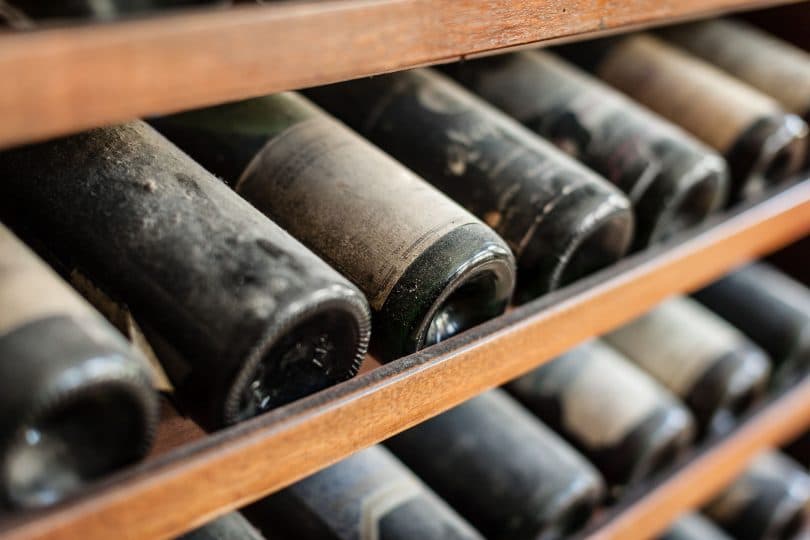 Garrafas de vinho envelhecidas enfileiradas em uma adega.