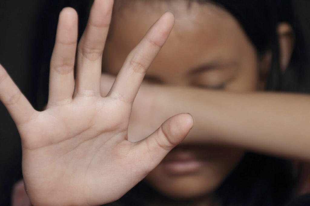 Menina com a mão no rosto se escondendo