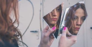 Mulher olhando seu reflexo no espelho triste