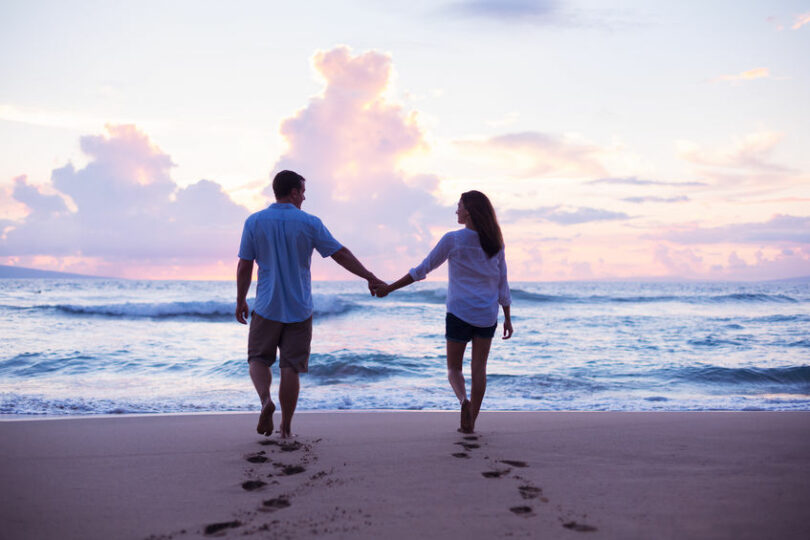 Casal de costas caminhando na praia