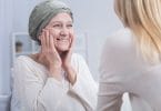 Mulher com câncer olhando e sorrindo para outra mulher a sua frente
