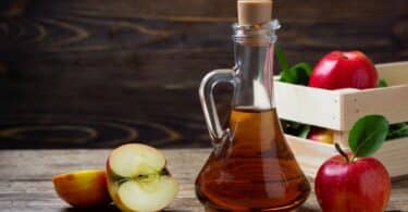 Imagem de um vinagre de maçã em um recipiente com maçãs do lado