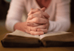 Mulher orando em cima da bíblia