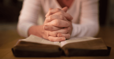 Mulher orando em cima da bíblia