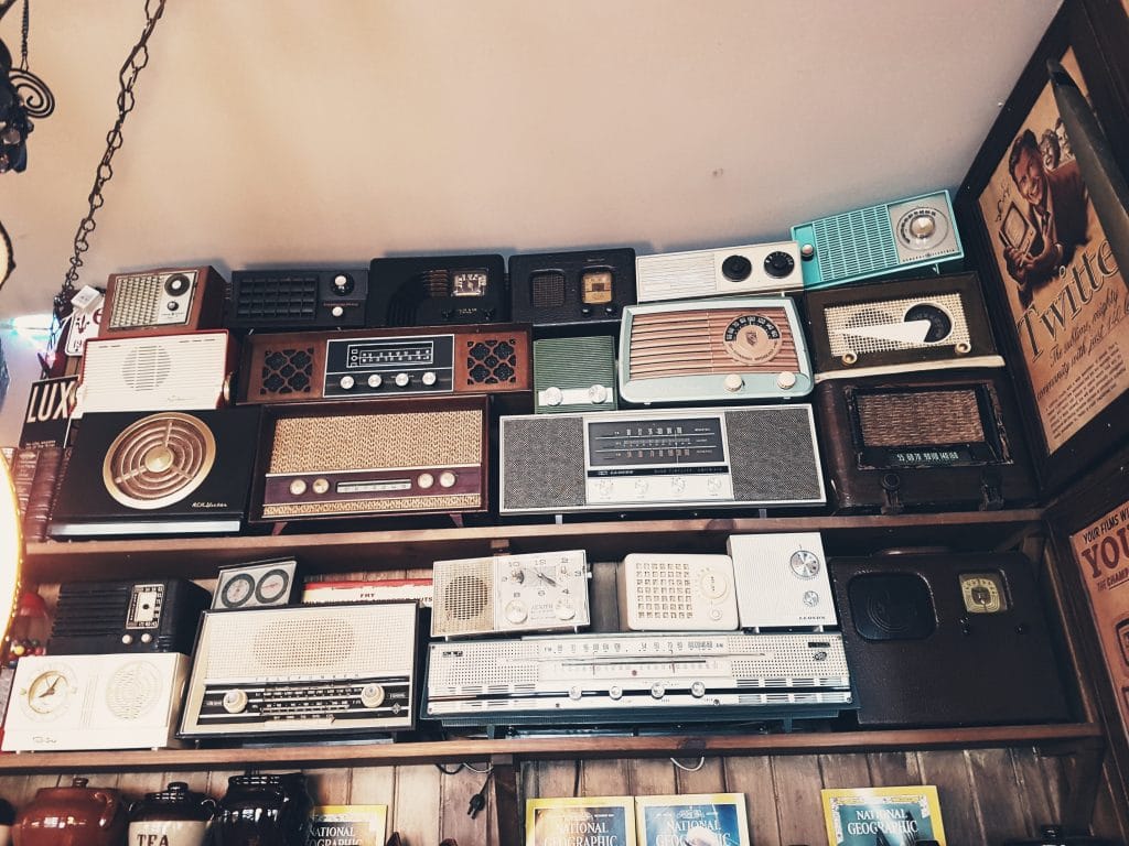 Prateleiras repletas de rádios antigos empilhados.