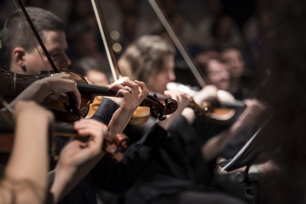 Imagem de músicos tocando violino em uma apresentação de música clássica.
