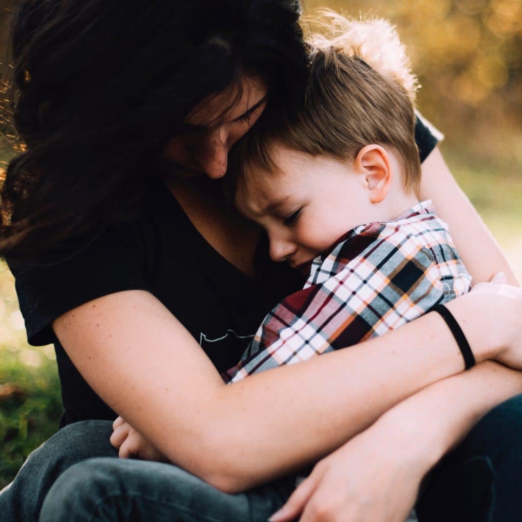 Criança triste no colo da mãe 