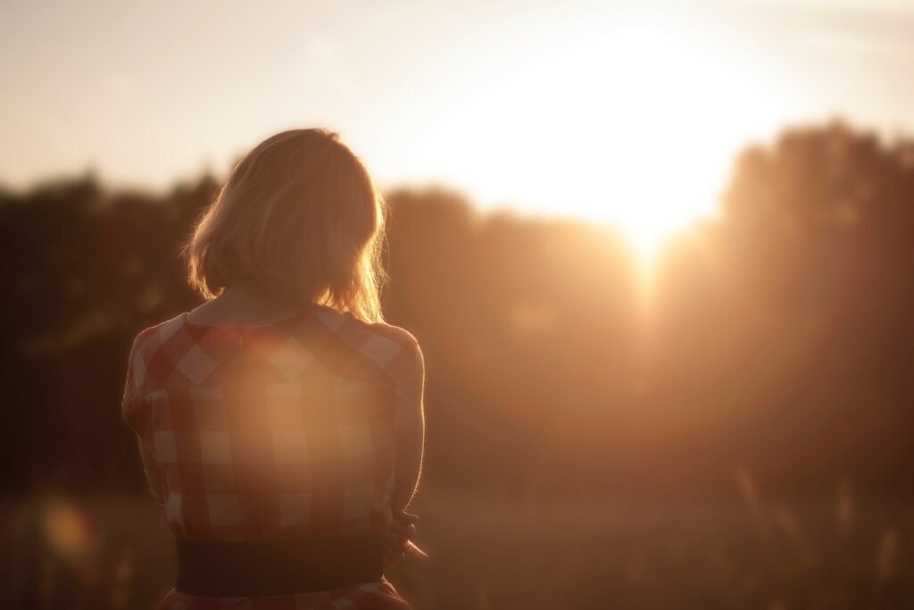 Mulher olhando para as árvores e para o sol 