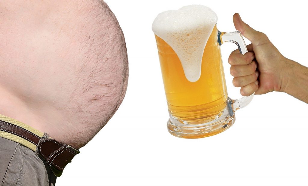 Imagem de uma barriga bem grande. É a barriga de um homem. Ao lado uma mão segurando um caneco cheio de cerveja.
