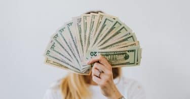 Mulher segurando notas de dinheiro cobrindo seu rosto