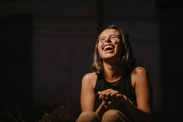 Garota sentada sorrindo de olhos fechados