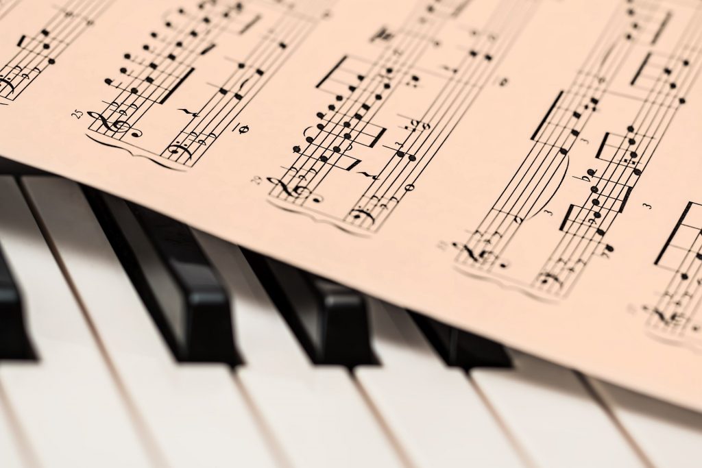 Imagem de uma partitura disposta sobre o teclado de um piano.