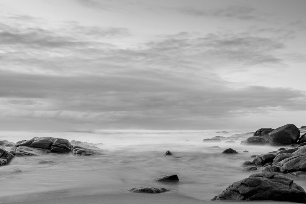 Imagem do mar de leite e junto algumas rochas e pedras gigantes.

