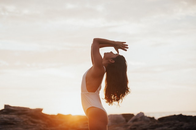 Mulher olhando para o alto com mãos em frente ao rosto com sol refletindo ao fundo