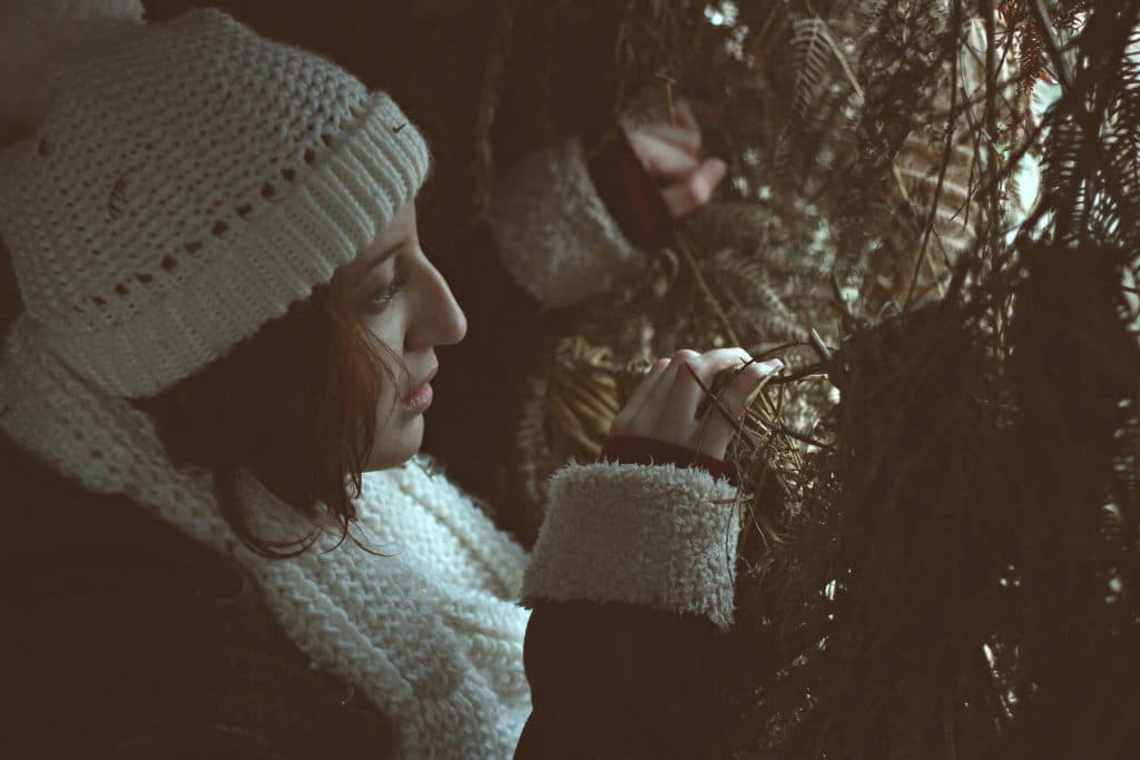 Mulher com roupas de frio olhando entre galhos