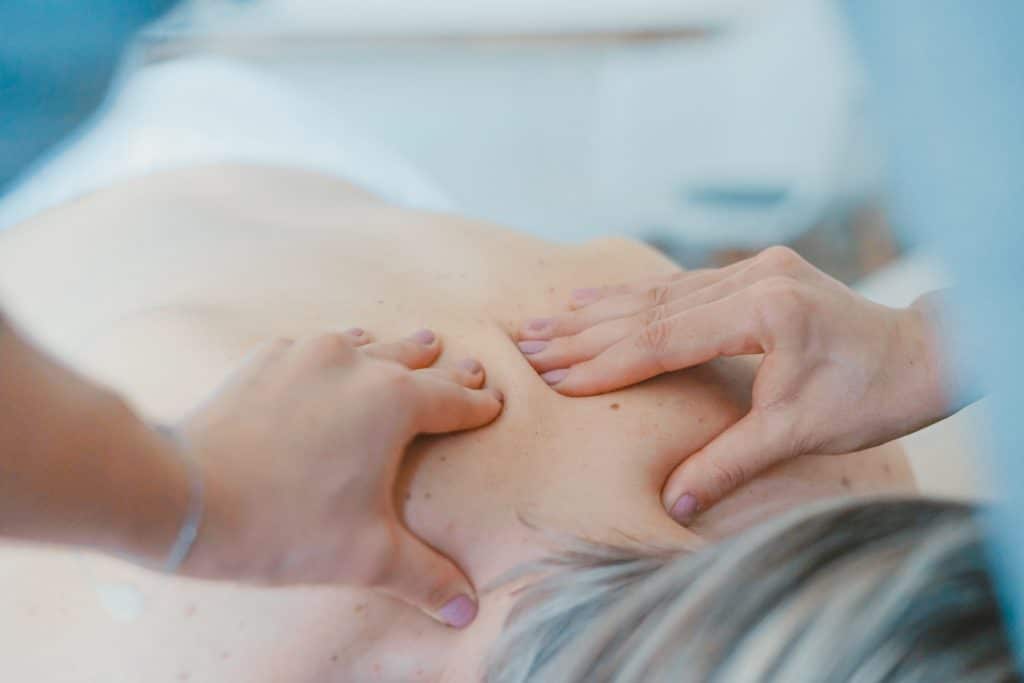 Mulher deitada em uma maca recebendo massagem