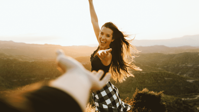 Mulher feliz com a mão estendida nos campos