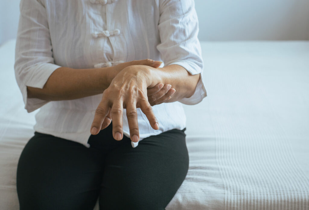 Mulher com mal de parkinson segurando seu braço