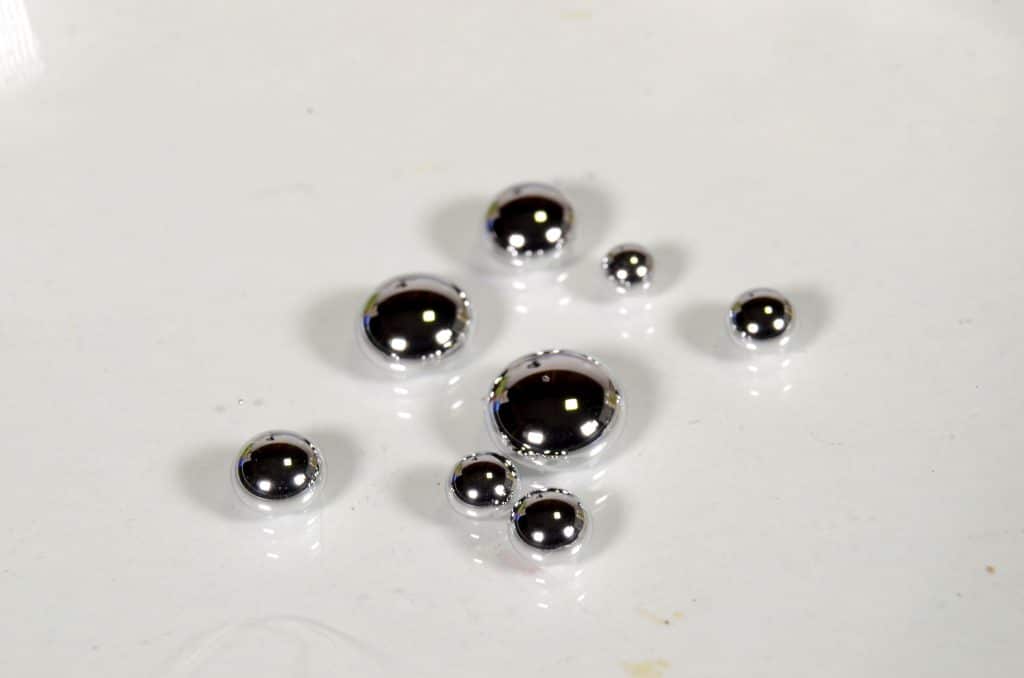 Gotas de mercúrio em uma superfície branca.