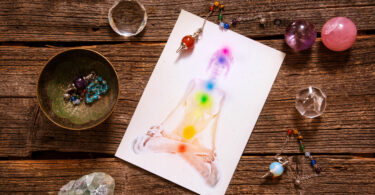 Chakras desenhado em um corpo de uma pessoa co pedras ao redor da mesa