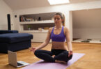 Mulher sentada em posição de meditação em frente a um computador.