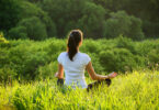 Mulher meditando em gramado no alto de montanha