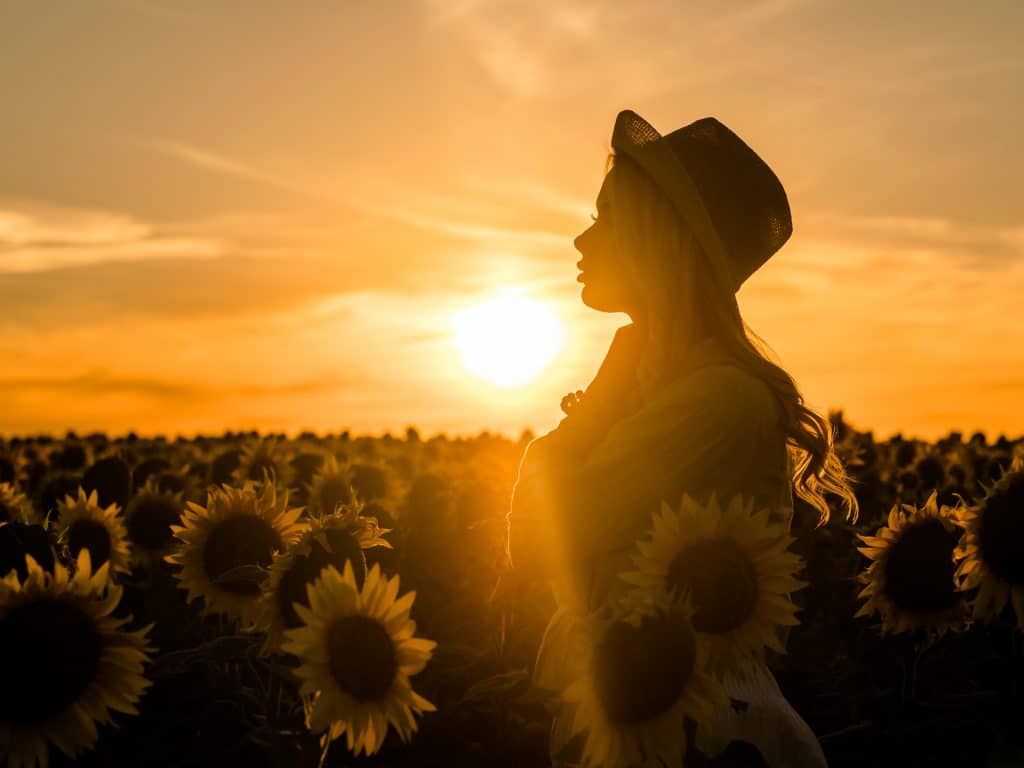 Mulher em um campo de girassóis pensativa