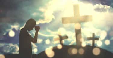 Um homem adora a Deus com três cruzes e luz do sol no céu.