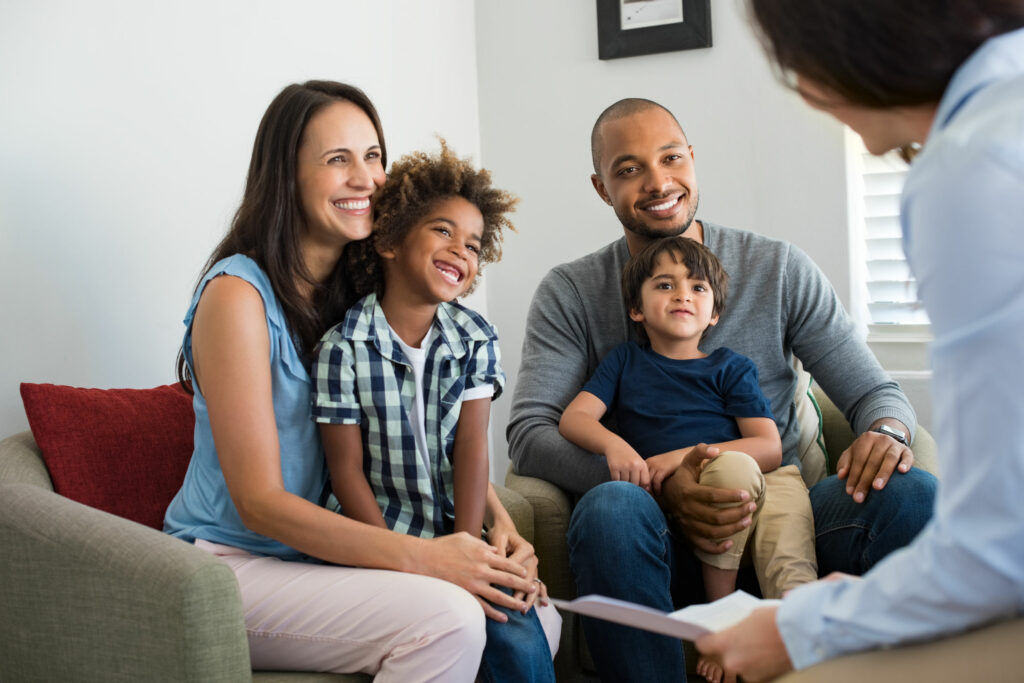 Família falando com um consultor enquanto homem e mulher seguram em seu colo crianças