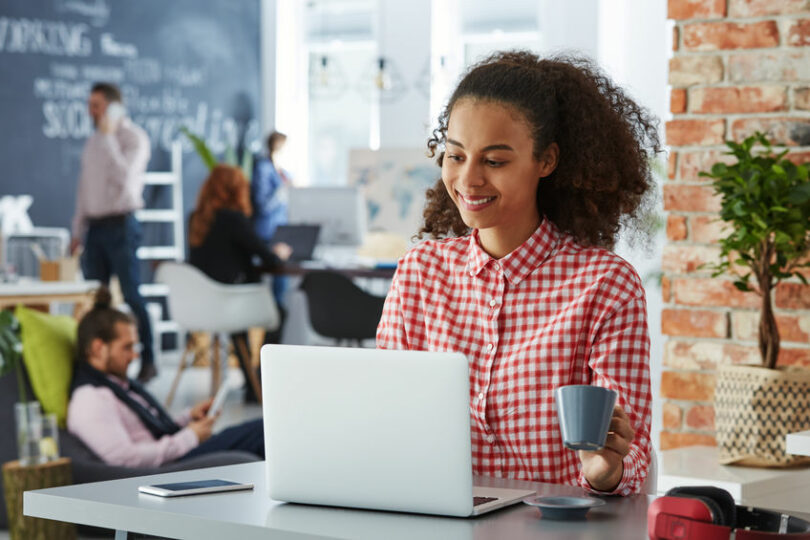 Mulher trabalhando sorrindo em espaço de cowork