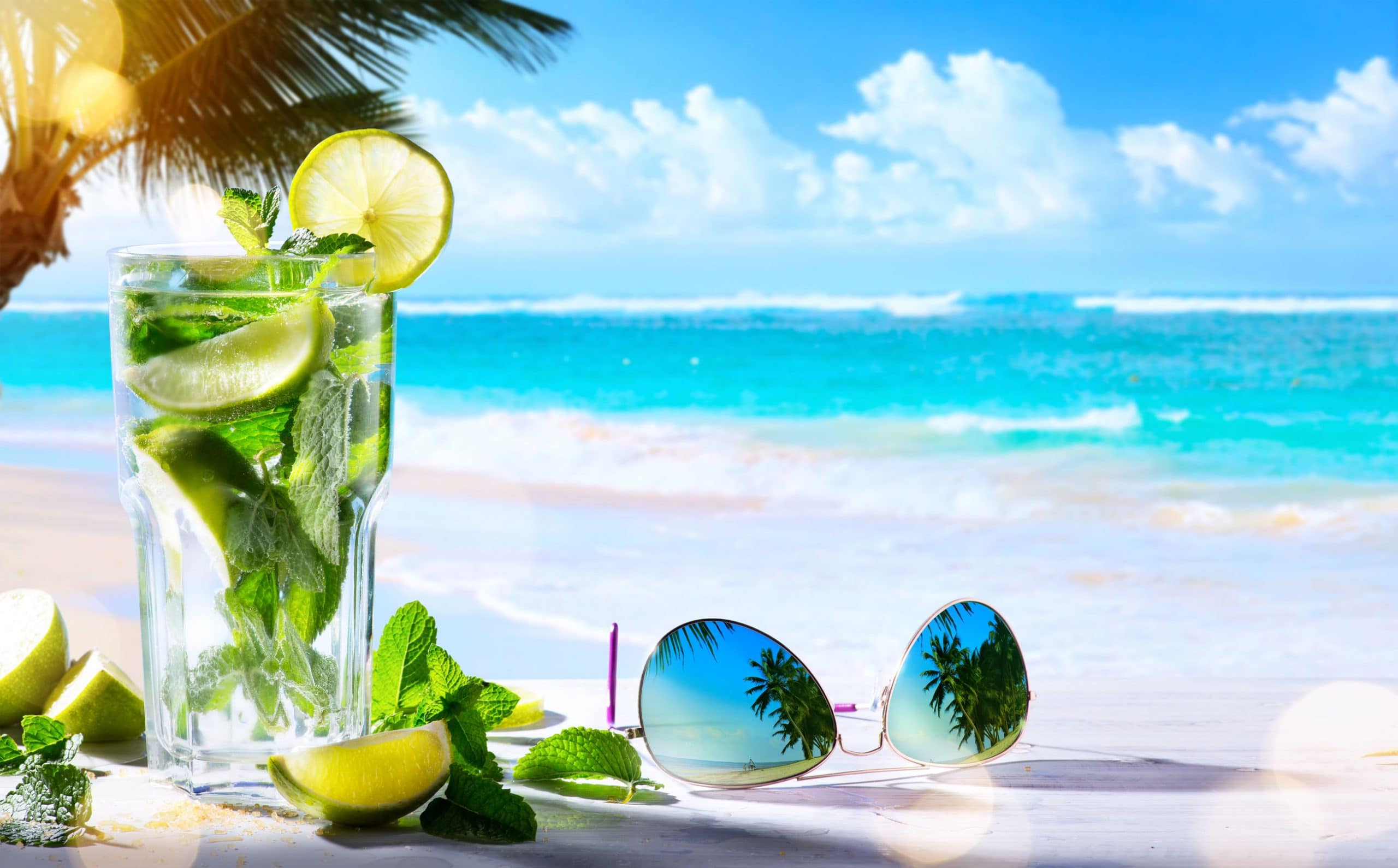Copo com bebida transparentes em uma praia.