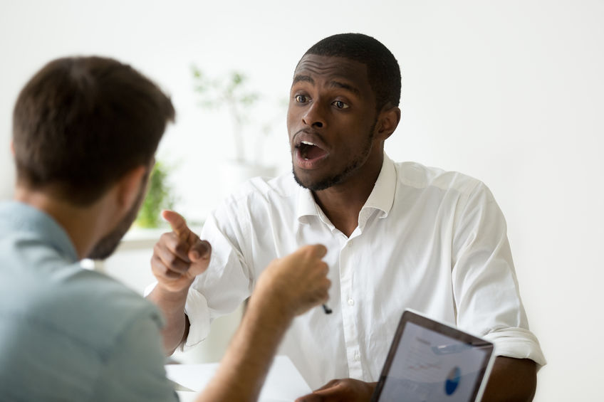 Dois homens discutindo frente a frente. Ambos estão apontando o dedo indicador para o outro.