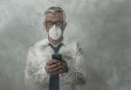 Homem mexendo no celular com máscara no rosto e fumaça ao redor