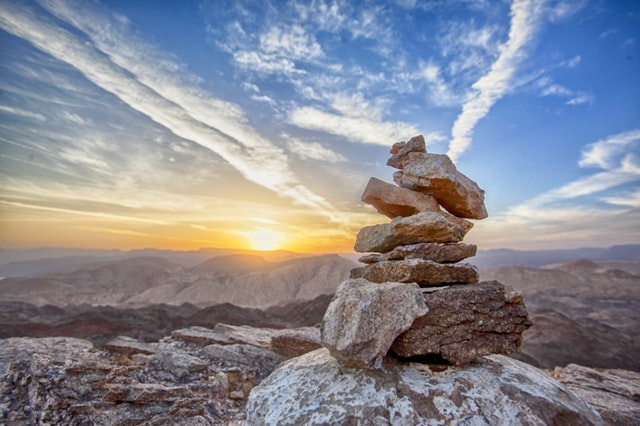 Conjunto de pedras vistas de cima com pôr-do-sol e e céu azul ao fundo