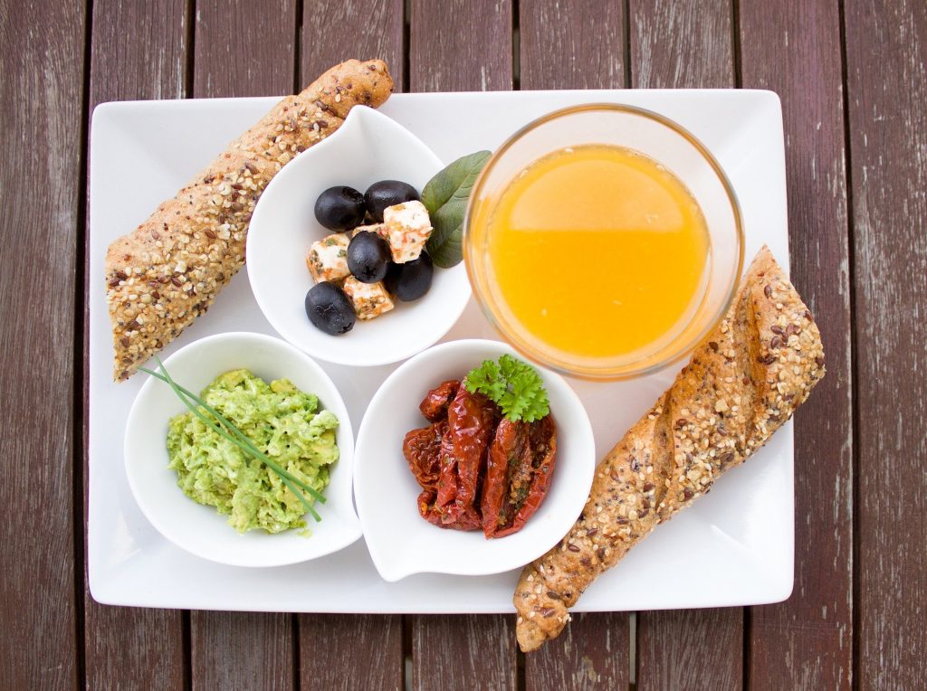Imagem de um prato com alimentos favoráveis para uma reeducação alimentar. O prato é composto por suco,  salada, frutas e pão integral.