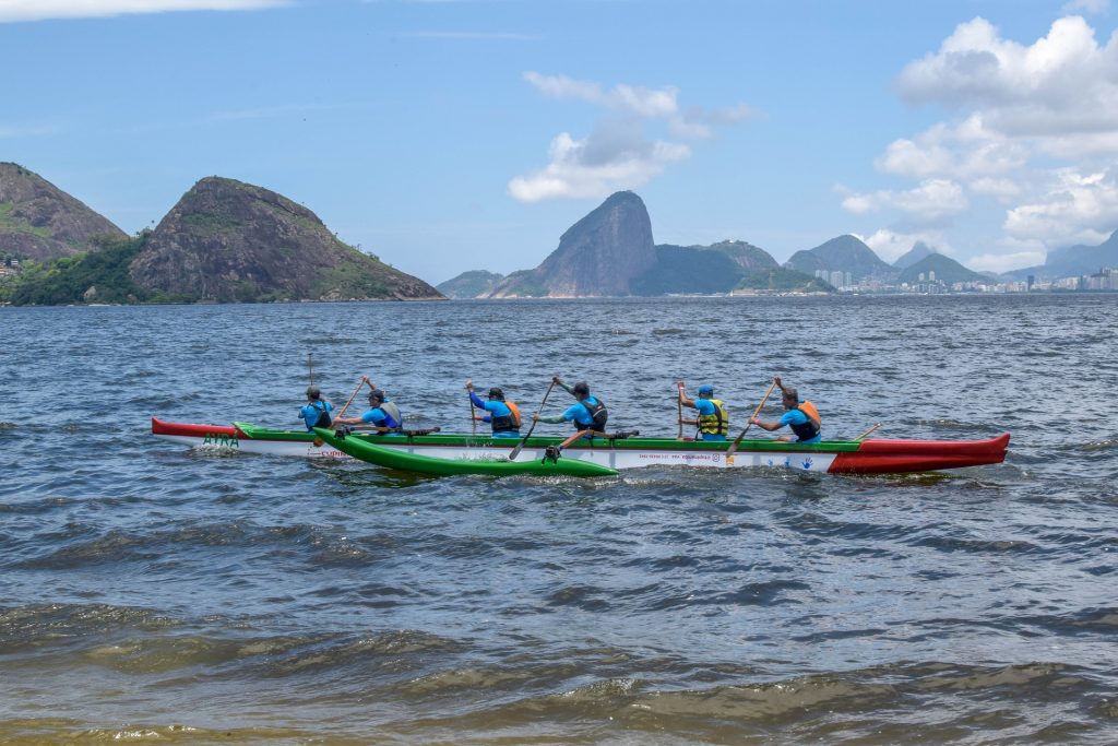 Grupo de homens vestindo coletes praticando canoagem em um lago na cidade do Rio de Janeiro.