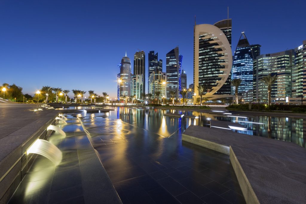 Imagem da linda cidade de Doha, localizada no Catar, cidade sede da Copa do Mundo de 2022. A cidade possui uma arquitetura futurista e é bem iluminada.
