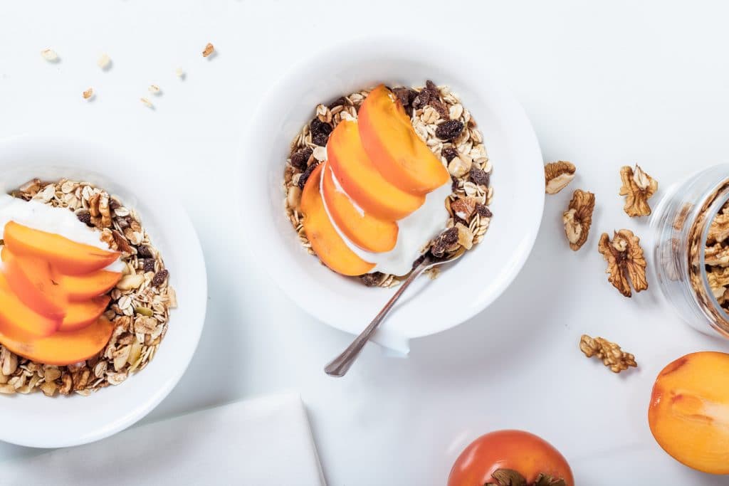 Tigelas com granola, leite e frutas.