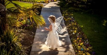 Criança andando em uma passagem de madeira vestida de fada