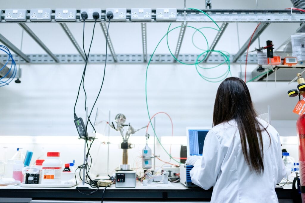 Imagem de um profissional de engenharia (mulher) dentro de uma sala de laboratório  pesquisado e estudando forma de extração do petróleo.
