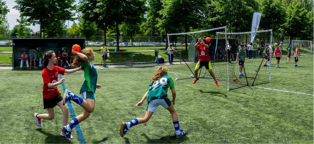 Mulheres em um campo de gramado. Elas estão treinando gols para a prática do jogo de handball.