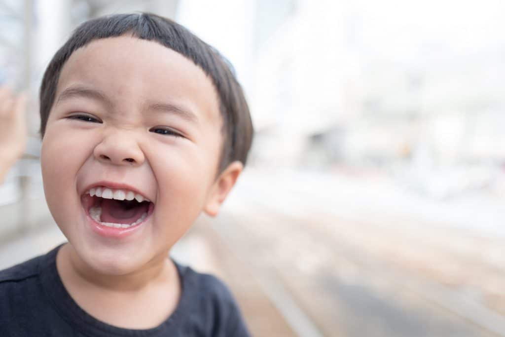 Criança sorrindo na rua durante o dia.