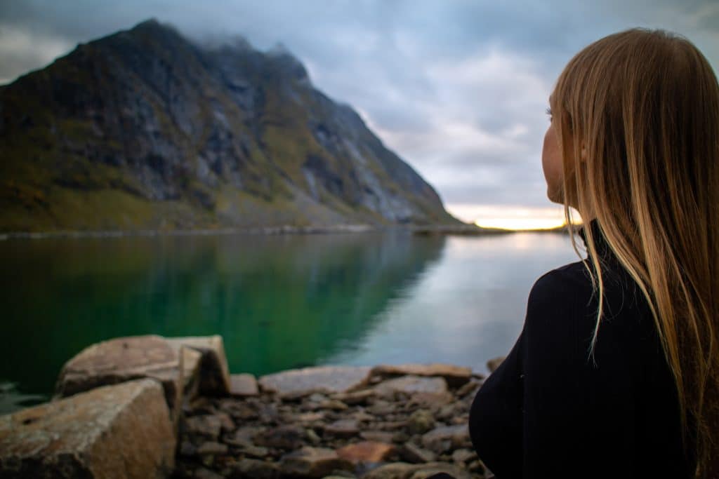 Menina olhando para uma montanha em um lago.