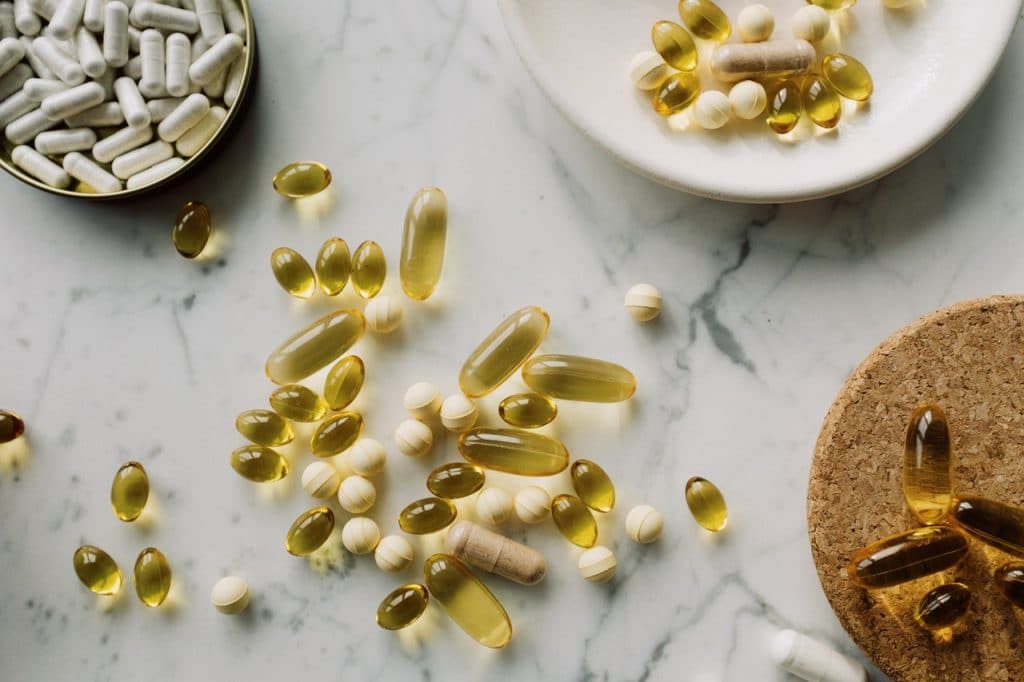 Suplementos vitamínicos em capsulas, pílulas e comprimidos, sobre uma mesa.