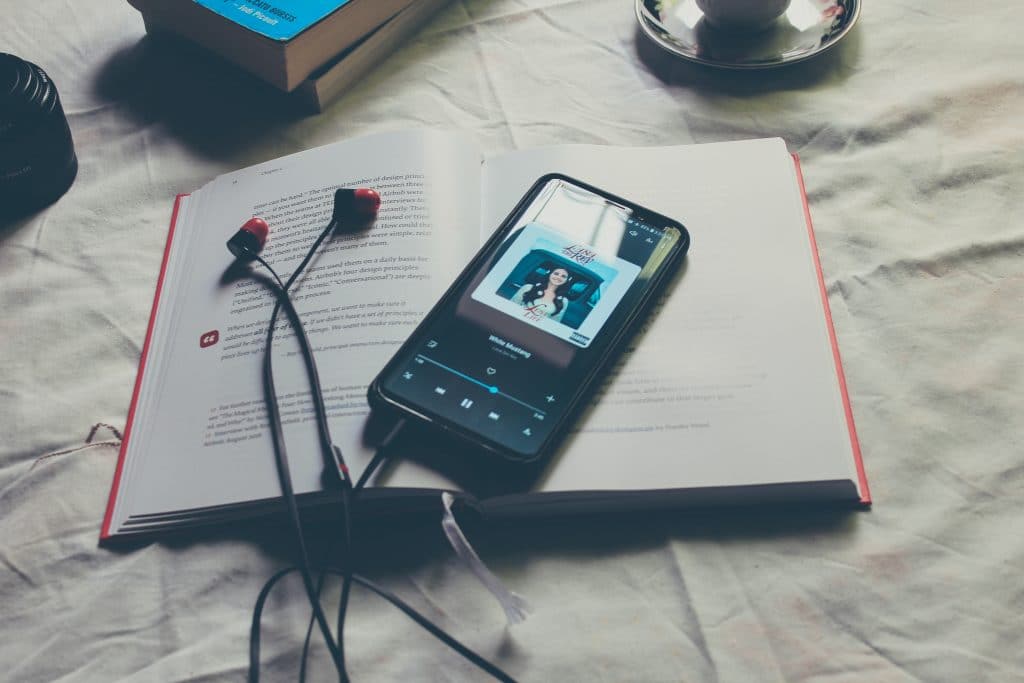 Mesa com um livro e celular ligando em alguma música