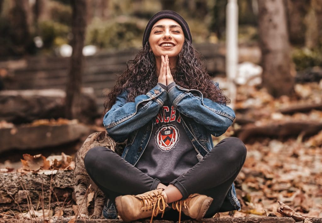 Mulher meditando e sorrindo ao meio da natureza